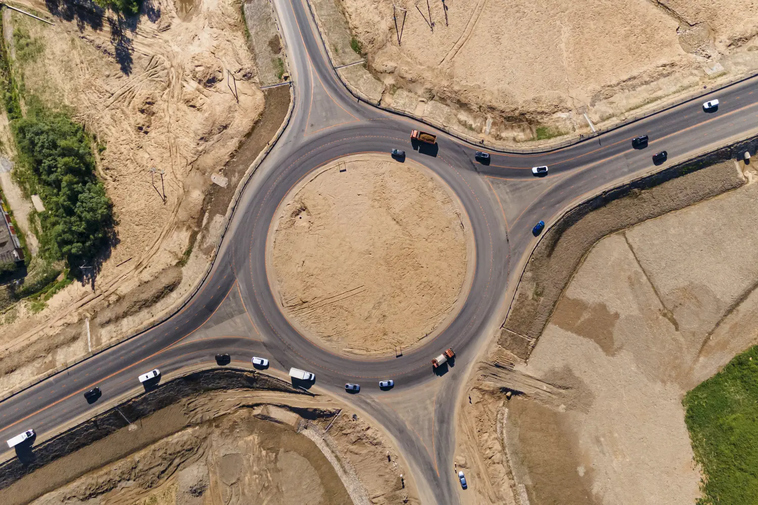 Top-down aerial view of a road roundabout with traffic and earthworks on both sides